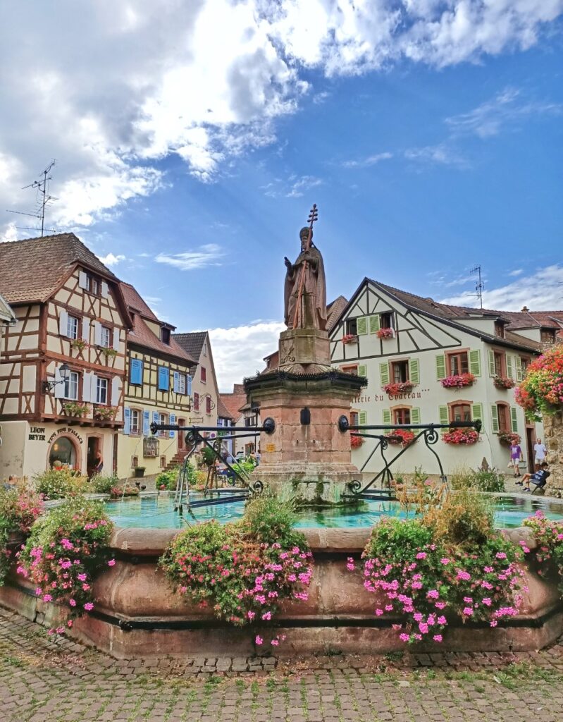 the fountain and typical houses of Eguisheim in Alsace, France