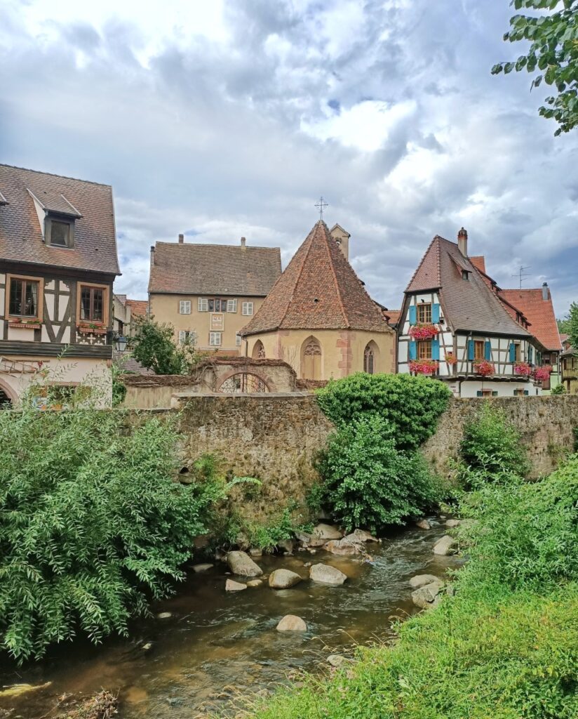 a river, bushes and medieval houses in Kayserberg, France