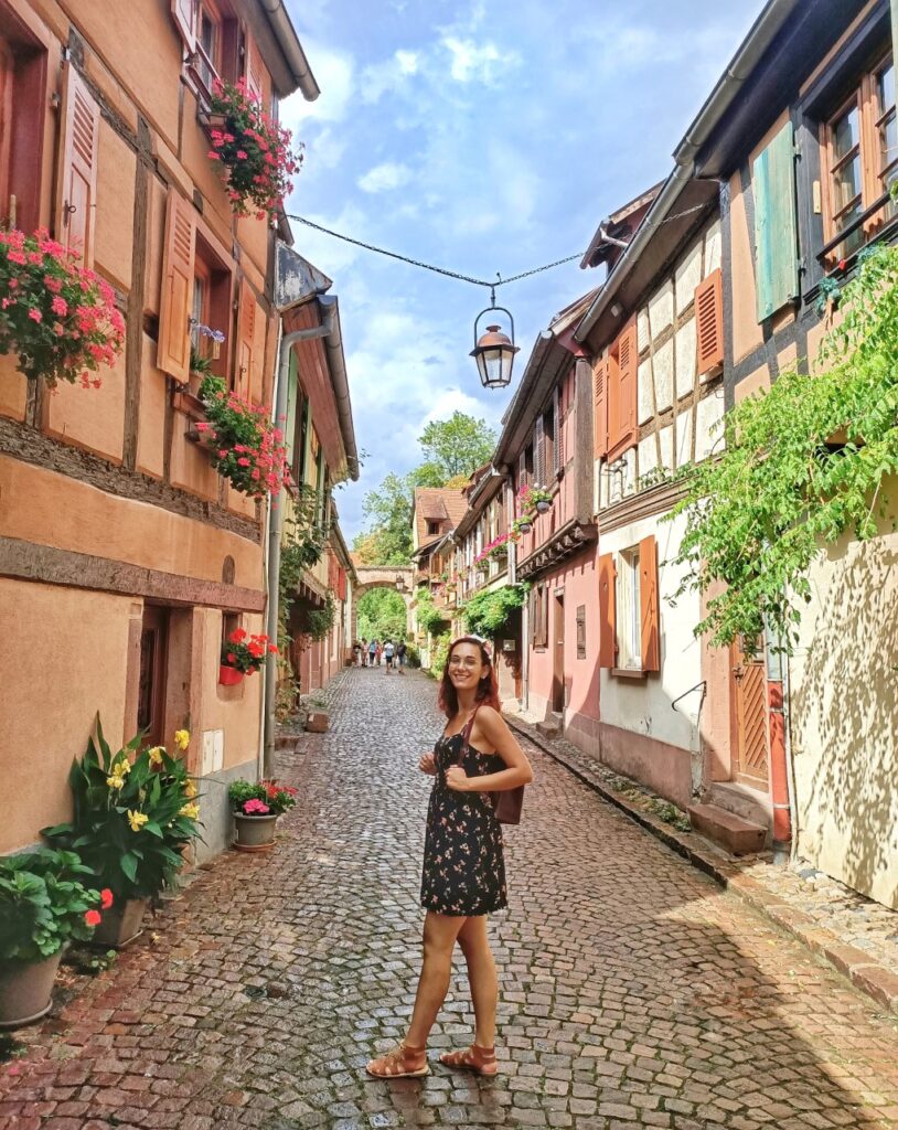 a small medieval street in kayserberg, Alsace with flowers and a paved road