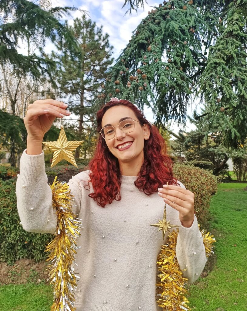 girl with christmas ornaments standing outside among pine trees and celebrating christmas