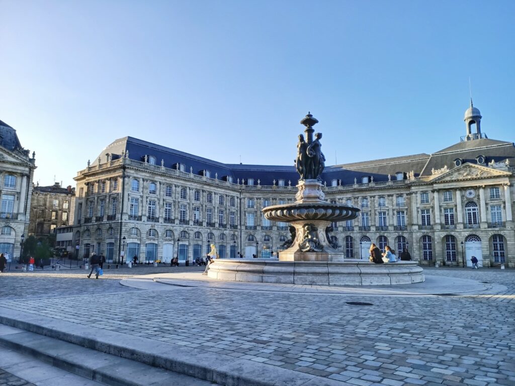 Place de la Bourse in Bordeaux, France. View of the central fountain, the paved ground and the neo-classical buildings in the background.
