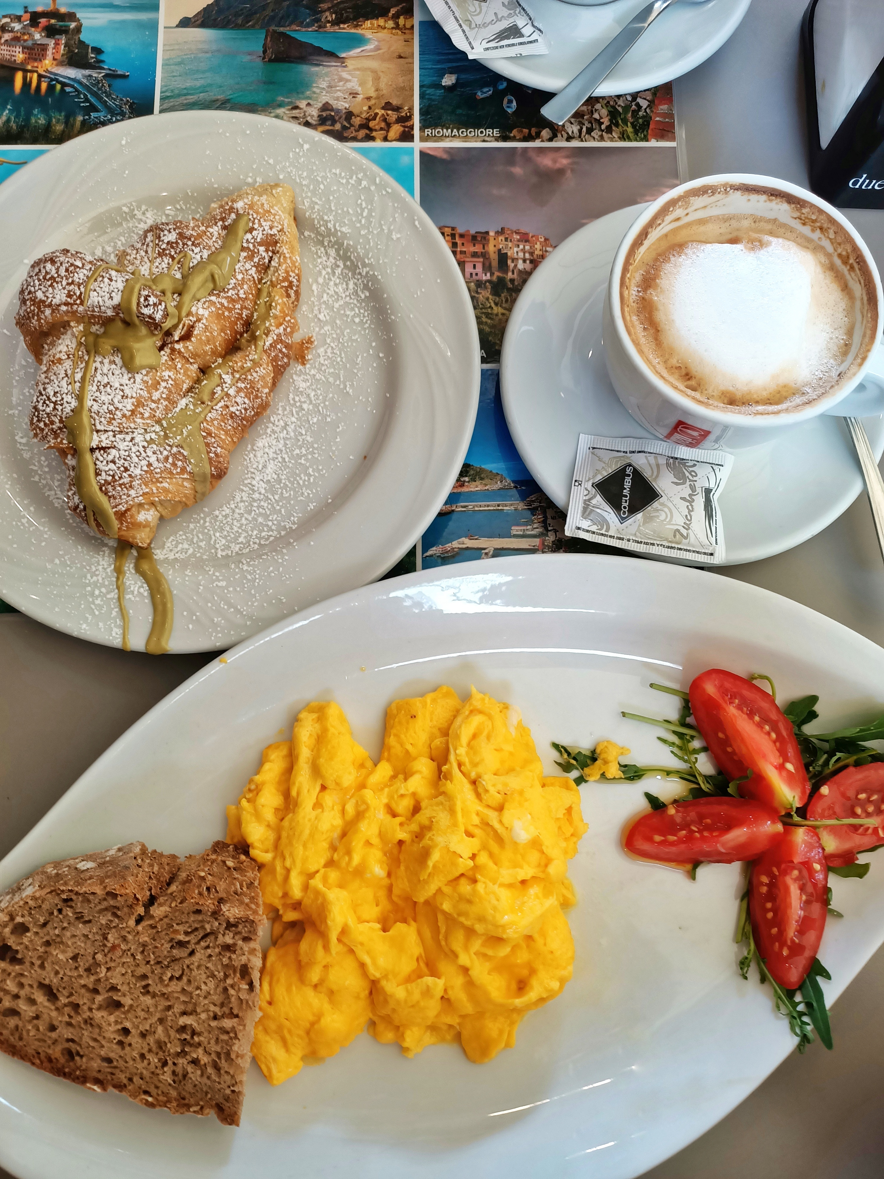 Breakfast at the restaurant Il Pirata delle Cinque Terre, in Vernazza, Italy. The plate contains their delicious scrambled eggs, with a cappuccino on the side and a pistacchio croissant.