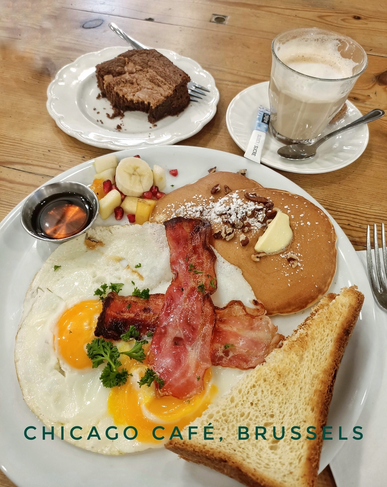 American brunch at Chicago Café in Brussels, Belgium. There are eggs and bacon, pancakes, toast and fruit on my plate. I also have a latte and a slice of brownie, all delicious!