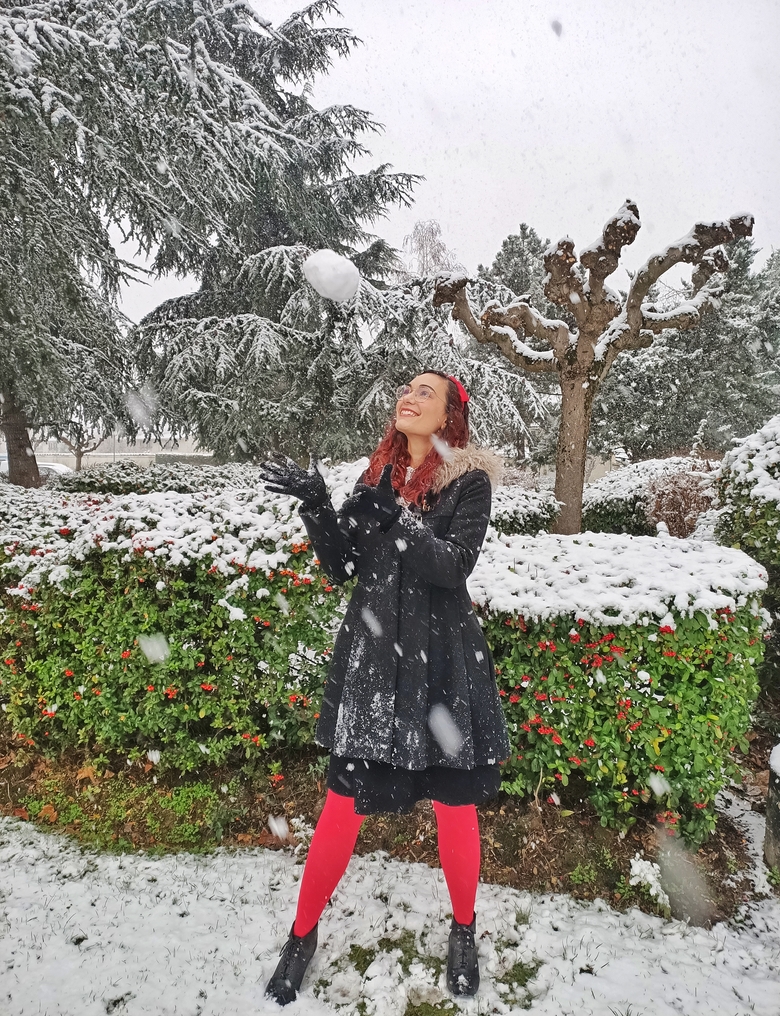 Picture of me playing in the snow. There are snowflakes all over the picture and snow on the trees and bushes. I am throwing a snowball in the air, happy to have a snowy winter.