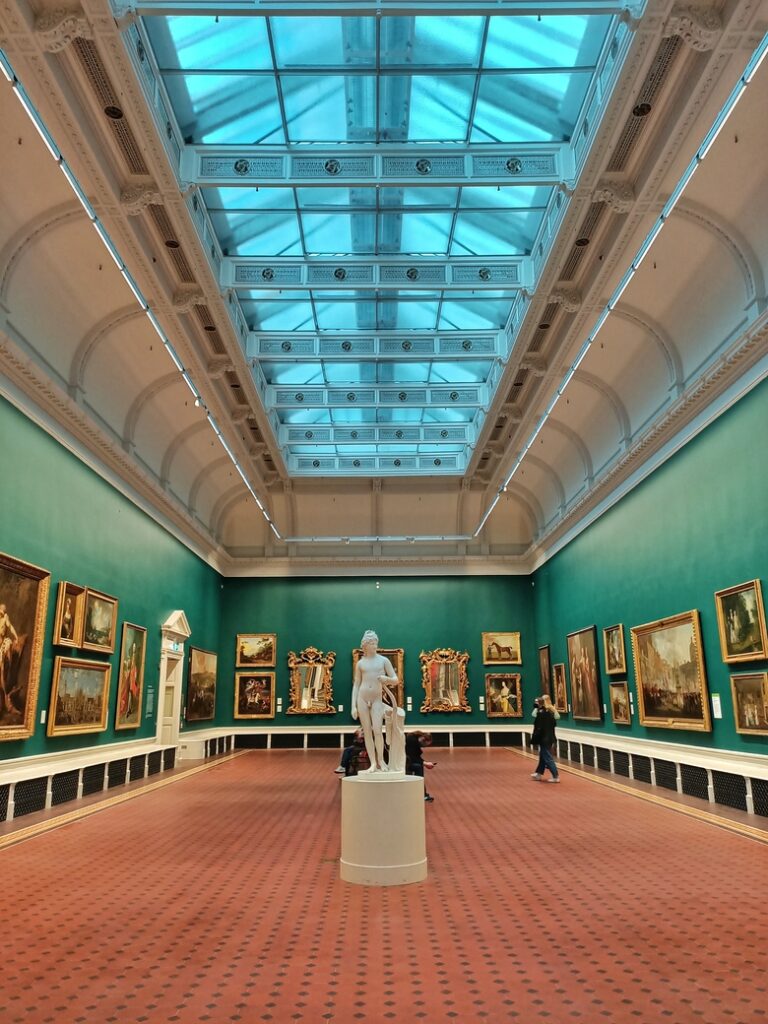 A room of the National Gallery of Ireland in Dublin. There is a sculpture in the centre of the room and there are paintings on the walls.
