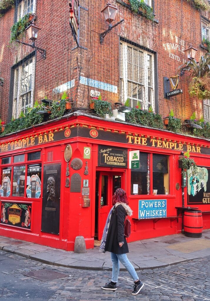 The famous Temple Bar pub in Dublin, Ireland. I am standing in front of the bright red facade of the pub.